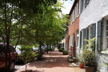 Colored facade of houses, windows with black shutters, green bushes, road near houses, horizontalの写真素材