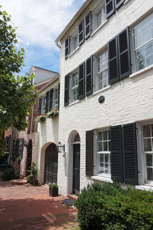 White facade of houses, windows with black shutters, green bushes, verticalの写真素材