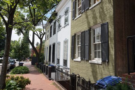 Colored facade of houses, windows with black shutters, green bushes, horizontalの写真素材