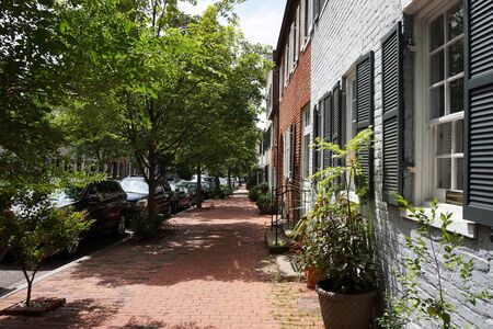 Colored facade of houses, windows with black shutters, green bushes, road near houses, horizontalの写真素材