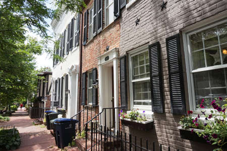 Colored facade of houses, windows with black shutters, green bushes, horizontalの写真素材