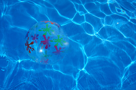Beach ball floating in a blue swimming pool. Summer background.の写真素材