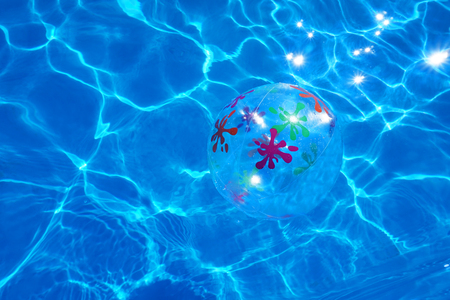 Beach ball floating in a blue swimming pool. Summer background.の写真素材