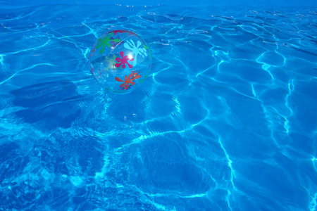 Beach ball floating in a blue swimming pool. Summer background.の写真素材