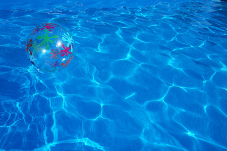 Beach ball floating in a blue swimming pool. Summer background.の写真素材