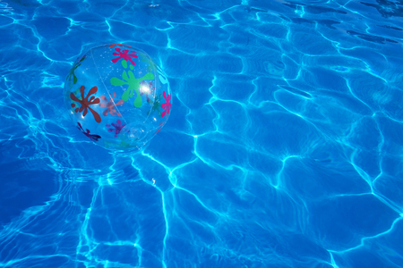 Beach ball floating in a blue swimming pool. Summer background.の写真素材