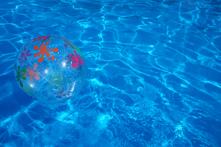 Beach ball floating in a blue swimming pool. Summer background.の写真素材