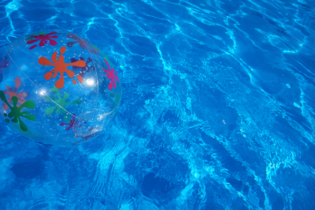 Beach ball floating in a blue swimming pool. Summer background.の写真素材