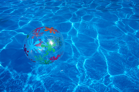 Beach ball floating in a blue swimming pool. Summer background.の写真素材