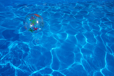 Beach ball floating in a blue swimming pool. Summer background.の写真素材