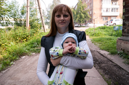 mom with a baby in her arms in the summer on the streetの写真素材