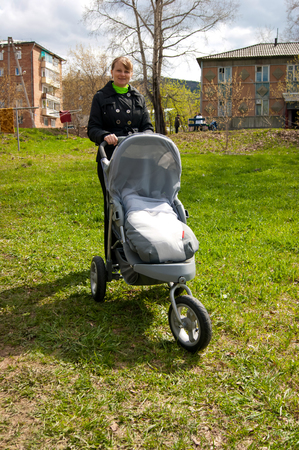 girl with a stroller and a baby in the spring on the streetの写真素材