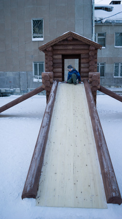 boy sitting on a wooden slideの写真素材