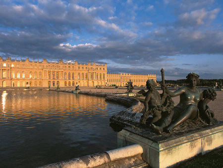 Versailles, France - 13 August 2014 : Bronze statue and exterior view of Versailles Palace ( Chateau de Versailles ) at sunset.のeditorial素材