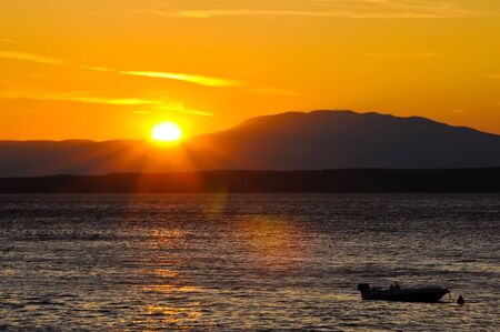 motor boat on the water against the background of mountains and sea sunsetの写真素材