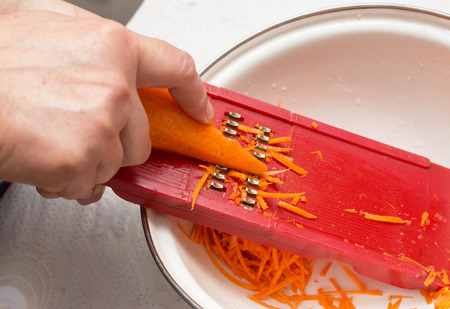 grated carrots on a graterの写真素材