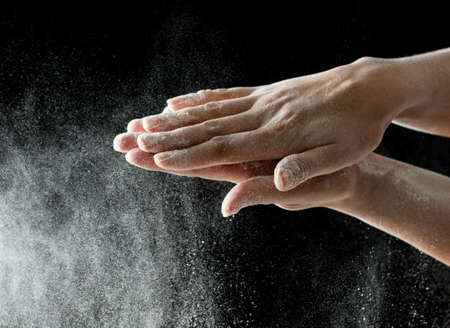White flour on hands on a black background