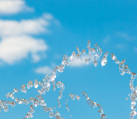 Water jet with spray on the sky background