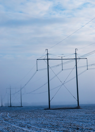 poles with electrical wires against a blue skyの写真素材