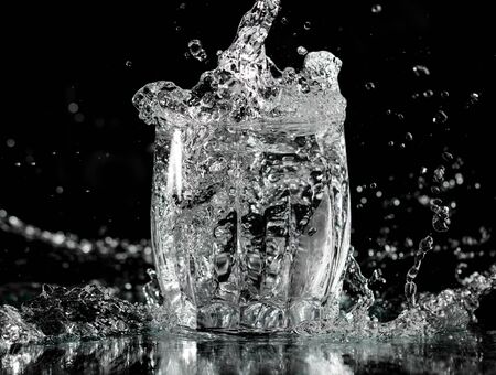splash and spatter of water in a glass on a black background