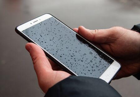 phone in men's hands in the rainの写真素材