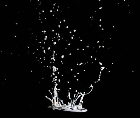 splashes and jets of milk on a black backgroundの写真素材