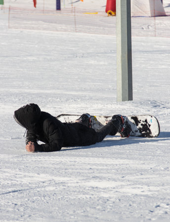 man fell off his snowboard into the snowの写真素材