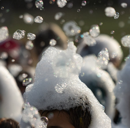 A group of people are playing in the water, with one person's head covered in bubbles. Scene is...