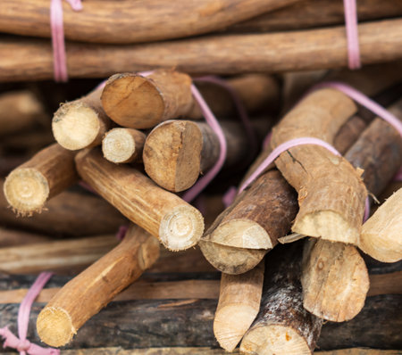 A pile of wood with pink strings tied to them. The wood is cut into small pieces and is arranged in...