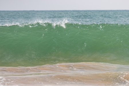The ocean is green and the waves are crashing. The water is calm and the sky is clearの写真素材