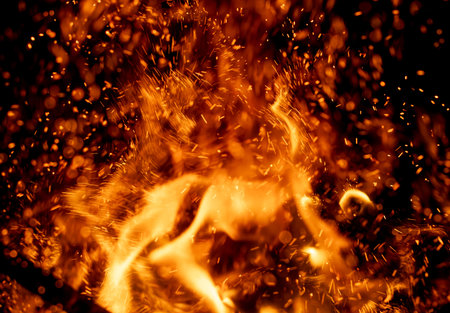 A fire with a lot of sparks. The fire is orange and the sparks are blackの写真素材