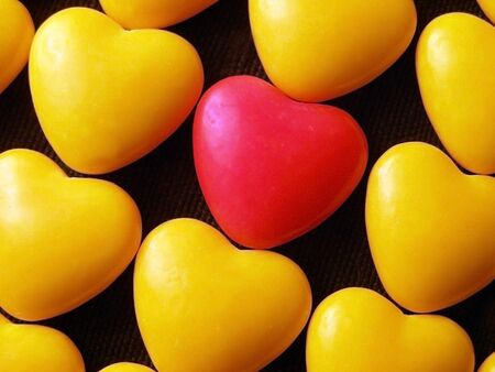 Pink candy heart surrounded by yellow hearts.の写真素材
