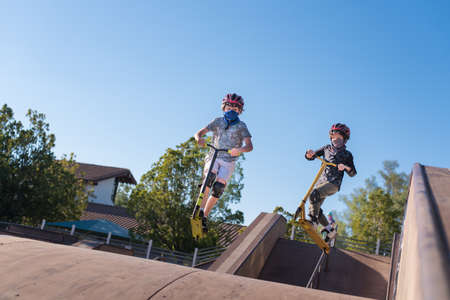 Two brothers catch a little air on their scooters at the local skate park