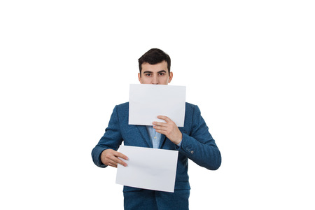 Portrait of a smiling businessman holding two white papers one hiding half face on a white background.の写真素材