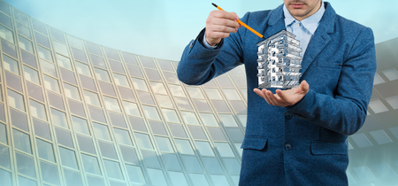 Property insurance.Businessman holding a pencil in his hand try to draw an imaginary apartment building.Real estate agent.の写真素材