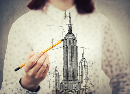 Young woman architect closeup sketching a construction project, the exterior of a skyscraper. Architectural drawing concept. Tall building business center plan.の写真素材