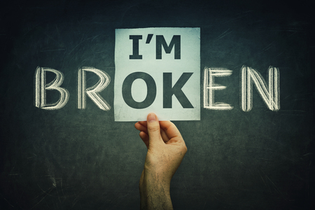 Hand holding a paper sheet the text i'm ok over blackboard background with the written chalk text i'm broken. Fake mask for hiding real emotion. Introvert vs extrovert feelings concept.の写真素材