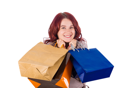 Happy girl shopaholic holding shopping bags to chest isolated over white background.の写真素材