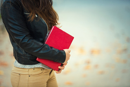 Close up of student girl body holding a red book, education concept.