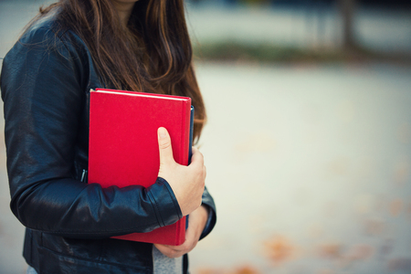 Young woman student holding books, close up view with copy space.の写真素材