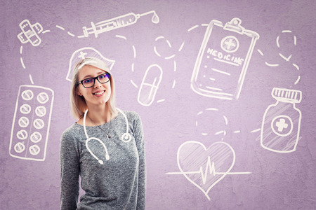 Beautiful cheerful young woman wearing glasses imagining her as a doctor.の写真素材
