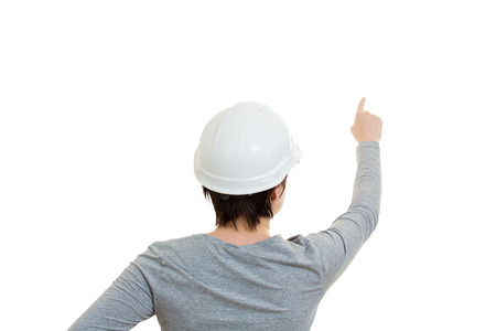 Rear view of young woman engineer wearing protection helmet pointing finger ahead isolated over white background.の写真素材