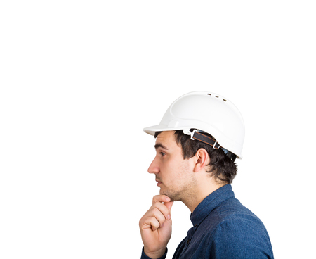 Side view of pensive man engineer hand under chin looking thoughtful wearing protective hard hat isolated over white background with copy space.の写真素材