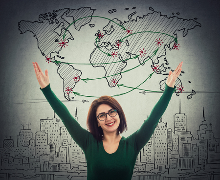 Cheerful businesswoman raising hands wide open celebrating over grey wallの写真素材