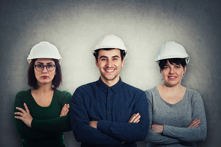 Team of three confident, positive thinking engineers wearing protective helmet and holding arms crossedの写真素材