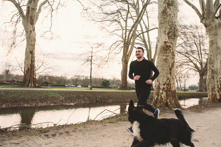 Young athlete running canicross with his border collie dog .Young Man runs with his dog city park. Healthy lifestyle concept.Active dog lifestyle concept.の写真素材