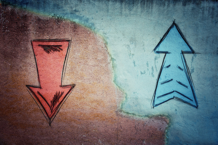 Split concrete wall cracked in the middle and arrows going in two different ways on red and blue side. Correct choice between up and down, failure or success. Difficult decision and doubt concept.の写真素材