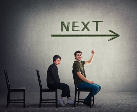 Unemployed persons sitting on chairs as candidates for a vacant job place waiting to be hired. Guy is next for employment interview. Business career development concept, job recruitment and leadershipの写真素材