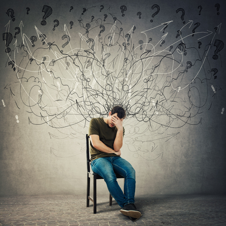 Pessimistic, disappointed man sitting on a chair in a dark room covering face with hand. Desperate guy seated alone suffer anxiety, distress depression feeling. Mess go out of head, losing memory.の写真素材