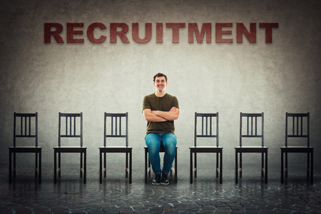 Young man sitting on a chair as perfect candidate for a vacant job place waiting to be hired. Business career development concept, job recruitment and employment. Human resources management choice.の写真素材